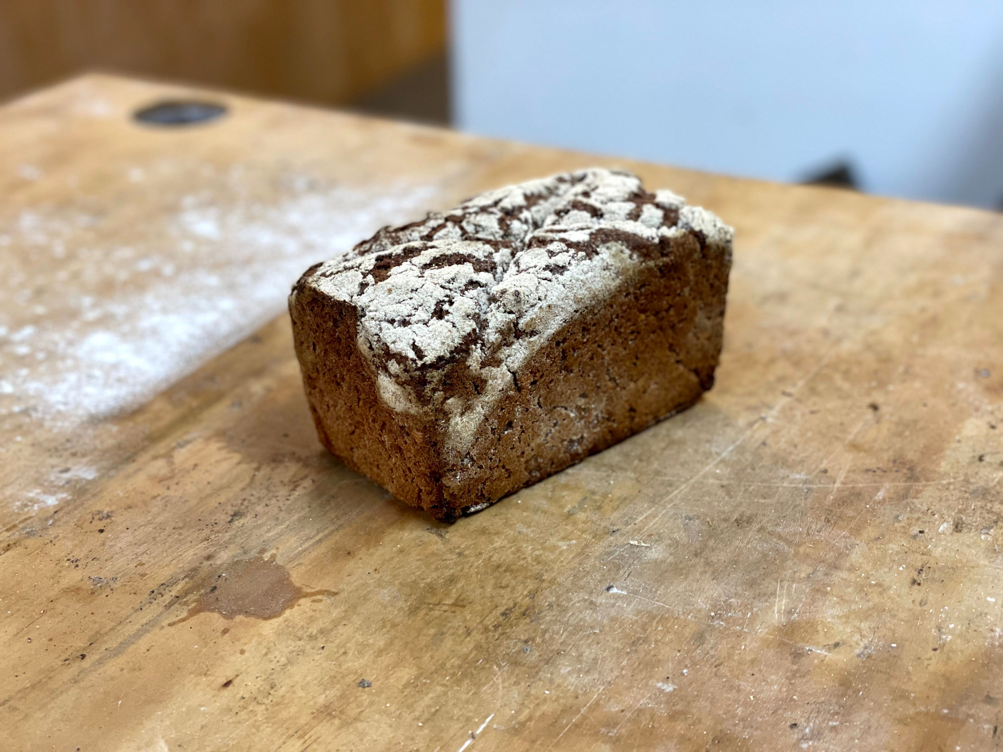 Close-up of a slice of whole grain bread with visible seeds on a neutral background